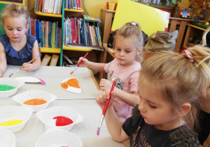 Dziewczynki malują farbami.