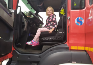 dziewczynka siedzi w wozie strażackim