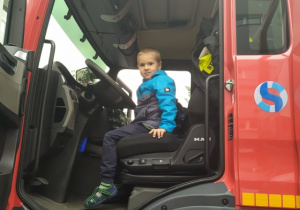 chłopiec siedzi w wozie strażackim