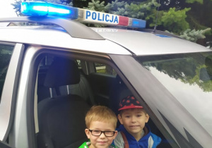 dwóch chłopców siedzi w radiowozie policyjnym