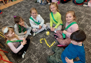Dzieci ułożyły cyfrę 2 z żółtych kółeczek na dywanie