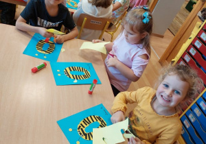 Dzieci tworzą osę z litery O z kolorowego papieru