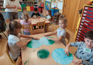 Dzieci malują palcami trawę po kartonowym kole