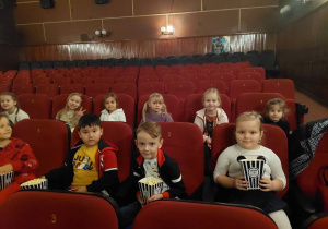 Dzieci siedzą z popcornem w kinie