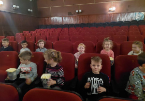 Dzieci siedzą z popcornem w kinie