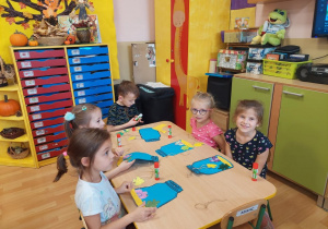 Dzieci wykonują pracę plastyczną przy stoliku