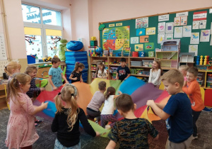 Dzieci bawią chustą animacyjną na dywanie