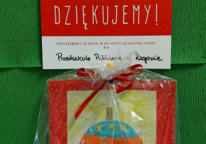 Czerwony dyplom z białym napisem "Szlachetna Paczka - Przedszkole Publiczne w Rzgowie