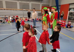 Dzieci stoją parami, jedno dziecko z przodu, drugie z tyłu i udają zaprzęg Świętego Mikołaja