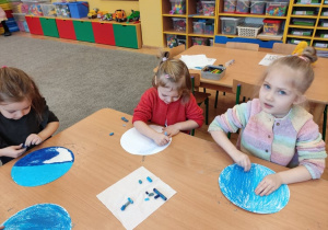 Dziewczynki malują pastelami swoje pracę.