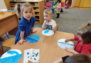 Dwie dziewczynki i chłopiec malują pastelami swoje prace.