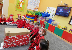Dzieci otwierają prezent od Św. Mikołaja.
