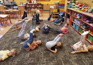 dzieci leżą na plecach na dywanie nogi trzymają pionowo wyprostowane
