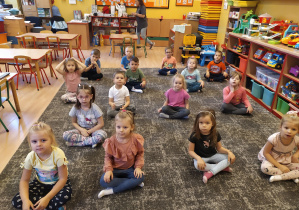 dzieci siedzą w siadzie skrzyżnym na dywanie