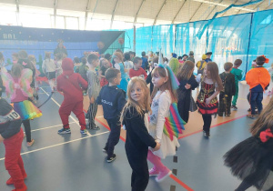 Dzieci przebrane za różne postaci z bajek tańczą w parach i w dużych kołach