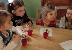 Cztery dziewczynki siedzą przy stoliku i piją napój.