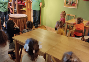 Dzieci siedzą przy stolikach i oglądają na spektakl.