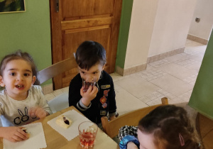 Dwie dziewczynki i chłopiec siedzą przy stoliku.
