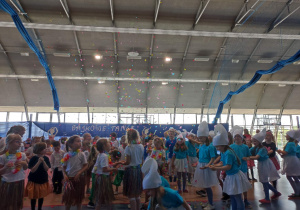 Duża grupa dzieci skacze i chwyta konfeti