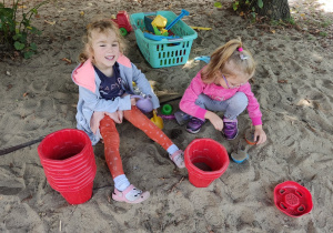 Dwie dziewczynki bawią się w piaskownicy.