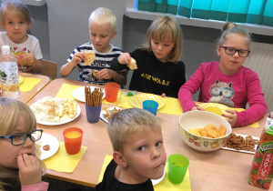 Dzieci jedzą przy wspólnym stole.