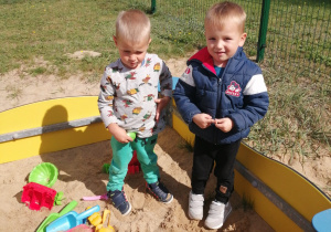 Dwaj chłopcy bawią się w piaskownicy.