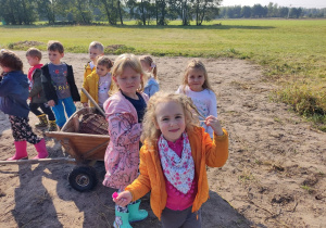 Dzieci stoją przy wózku w polu.