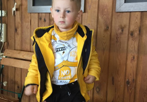 Chłopiec w żółtej kurtce depcze kapustę w beczce.