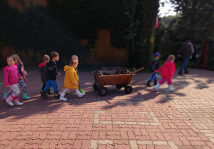 Grupa dzieci ciągnie wózek.