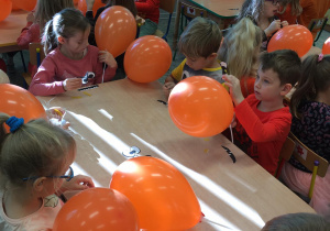 Dzieci naklejają oczy i buzie na balony.