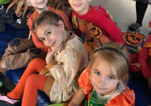Dzieci w jesiennych strojach uśmiechają się do zdjęcia.