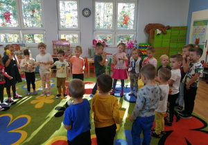 Dzieci stoją w kole i grają na instrumentach muzycznych.