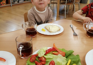 Chłopiec uśmiecha się jedząc paprykę.