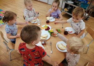 Dzieci siedzą przy stoliku podczas śniadania.
