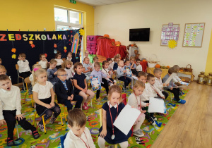 Dzieci siedzą na krzesełkach podczas uroczystości "Pasowania na Przedszkolaka".