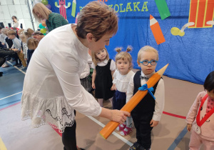 Pani Dyrektor pasuje na przedszkolaka dzieci poprzez dotknięcie czarodziejskim ołówkiem