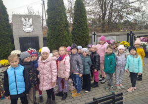 Dzieci stoją przed pomnikiem nieznanego żołnierza.