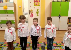 Dzieci w postawie na baczność śpiewają hymn narodowy "Mazurek Dąbrowskiego".
