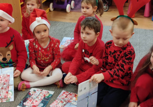 Grupa dzieci rozpakowuje prezenty od Mikołaja.
