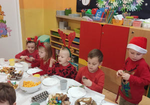 Grupa dzieci zajada słodkości przy stoliku.